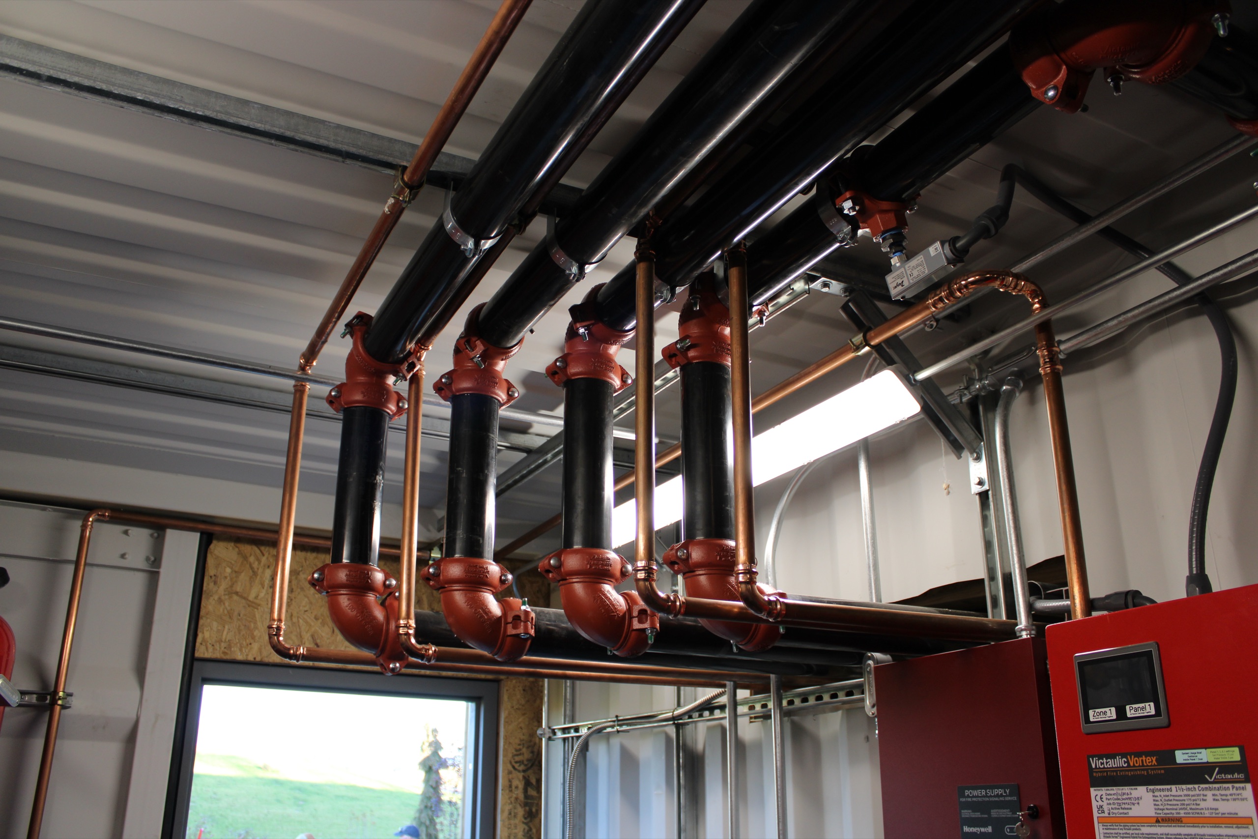 Black and copper piping above a fire suppression control panel